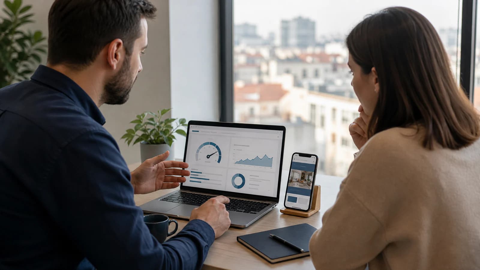 Business owner and web specialist reviewing website speed on a laptop and phone in a Bucharest office